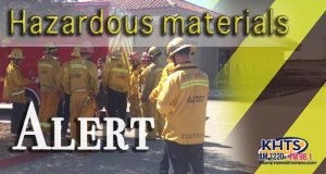 Louie: Hazardous Materials slider_Firefighters in group looking on at structure, reads "Hazardous Materials Alert"
