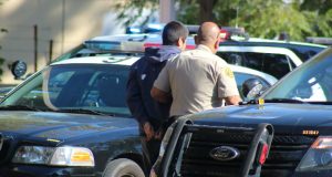 A deputy escorts one of the detained suspects into a squad car.