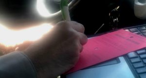A picture of a deputy writing a red tag for a vehicle.