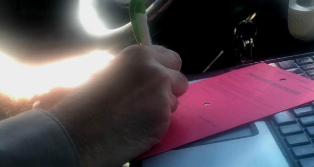 A picture of a deputy writing a red tag for a vehicle.