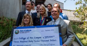 A picture of Wilk, Smith, and several COC officials with a large check