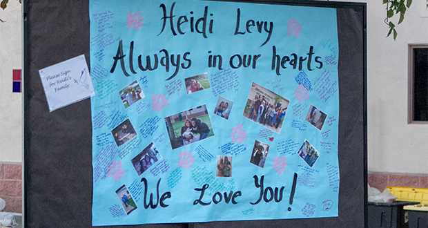 A paper banner encouraging guests to leave written messages for Heidi's family, featuring photos of Levy.