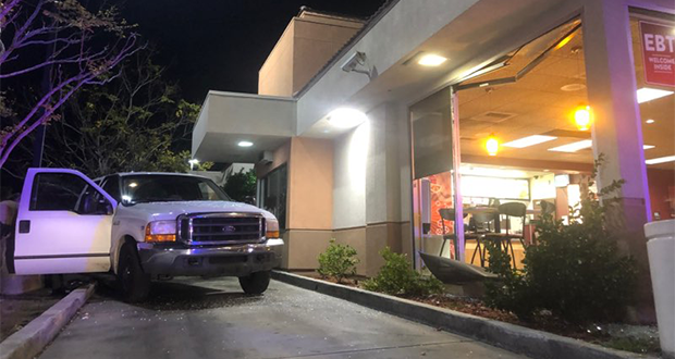 The white truck sideways in the drive-thru, rolled back from the freshly broken window.