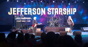 Jefferson Starship on stage, playing in front of a large crowd.