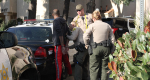 A suspect being searched up against a SCV Sheriff unit vehicle.