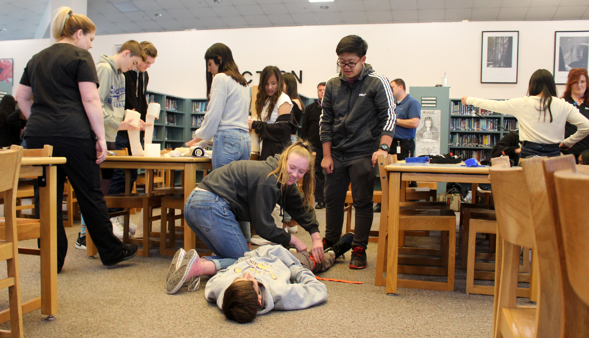 Valencia High School students practice applying tourniquets leg wounds.