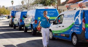 Allbright Painting representative runs towards camera with company vans in background