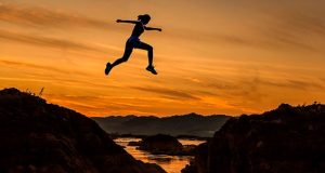 Woman Jumping across mountain