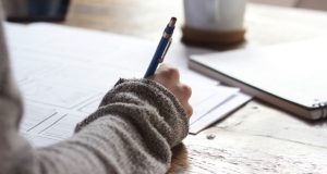 Student writing at desk