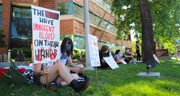 A sign in front of City Hall reading "The polive have innocnet blood on their hands."