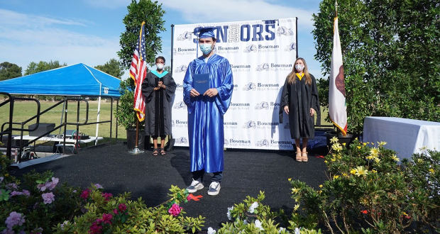 One student on the erected stage at Central park, holding their diploma.