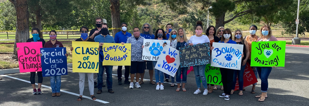 Family members holding signs of support for graduates.
