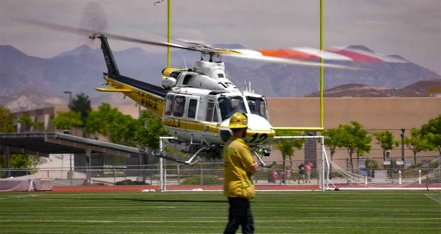 A helicopter landing on the 50 yard line of the Golden Valley Grizzlies' field.