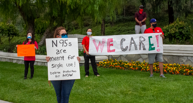 Henry Mayo Nurse holding a sign reading "N95s are meant for single use! Defense Production Act NOW"