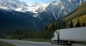 Truck riding up road with snow cap mountain ahead