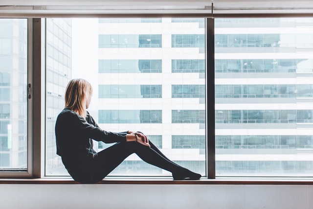 Woman sitting on office window sill