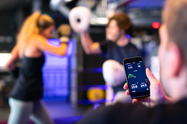 Women boxing while man tracks on phone app