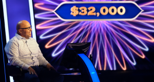 Oliver Fry sitting on stage for the game show.