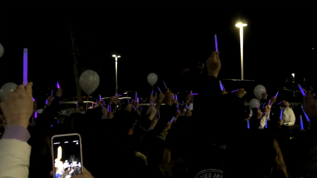 The crowd raises their glow sticks in the air.