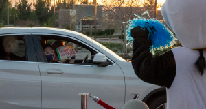 A prom guest in the passenger seat holding a sign reading "Night to Shine 2021"