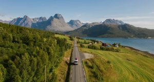 Scenic aerial view of camper van with canoe on roof road in Norwegian countryside in summer