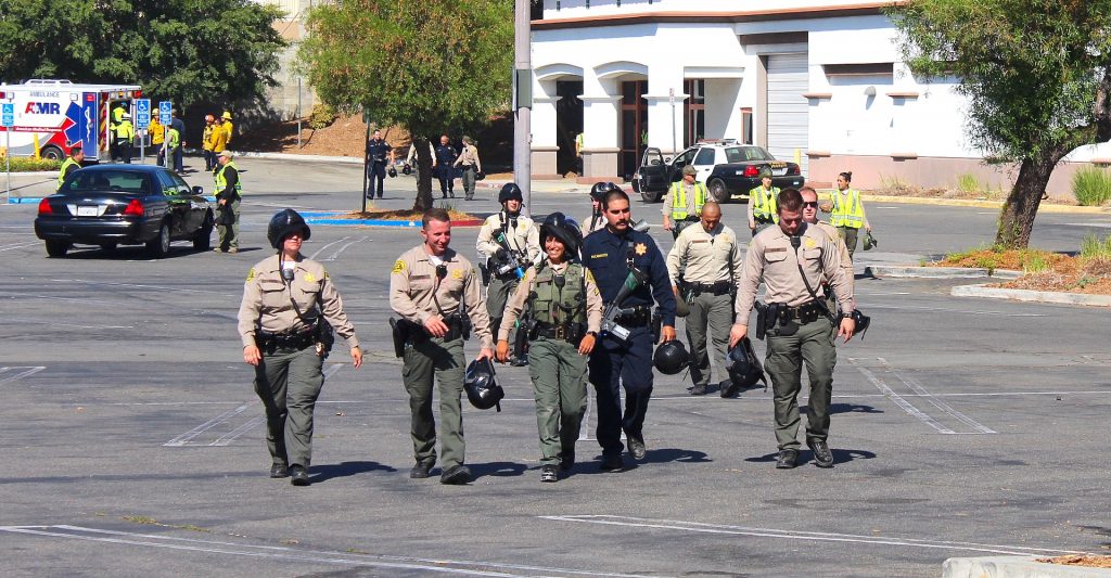 Deputies walk away from old Sears building with ambulance in the background