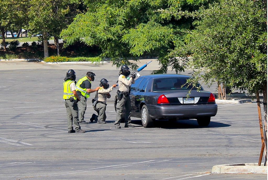 Deputies crouch behind a squad car